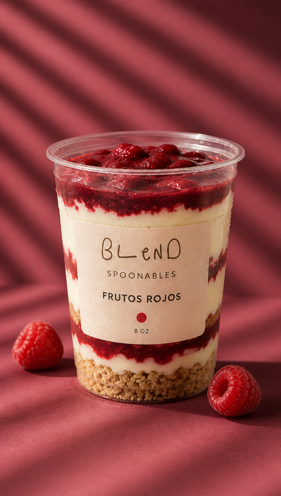 Vaso de Spoonables con capas de frutos rojos y yogur sobre fondo berry